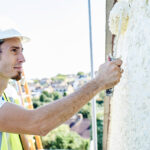 Worker painting outside of a house