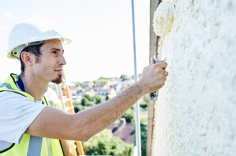 Worker painting outside of a house