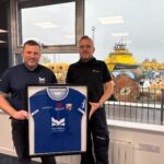 MPA Harbour Master, Ross Marshall, gifting Brage Viking Captain, Jan Pedersen, a Montrose FC t-shirt with proceeds going to PoppyScotland to mark the 1GWh milestone