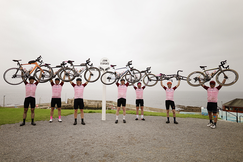 Cyclists holding bikes aloft following charity challenge