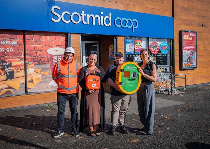 Peter Goldie, Regional Health, Safety and Environmental Advisor for Taylor Wimpey East Scotland, delivers a defibrillator and external cabinet to Scotmid