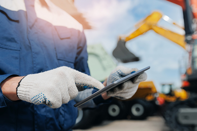 Industrial worker using tablet amidst heavy machinery at mining site